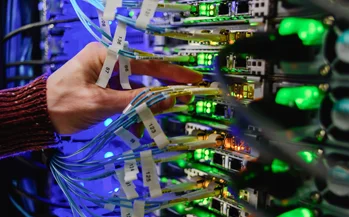 Technician connecting fiber patch cables in a communications equipment rack